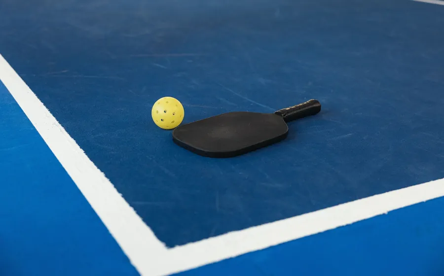 Vợt và bóng pickleball trên mặt sân xanh